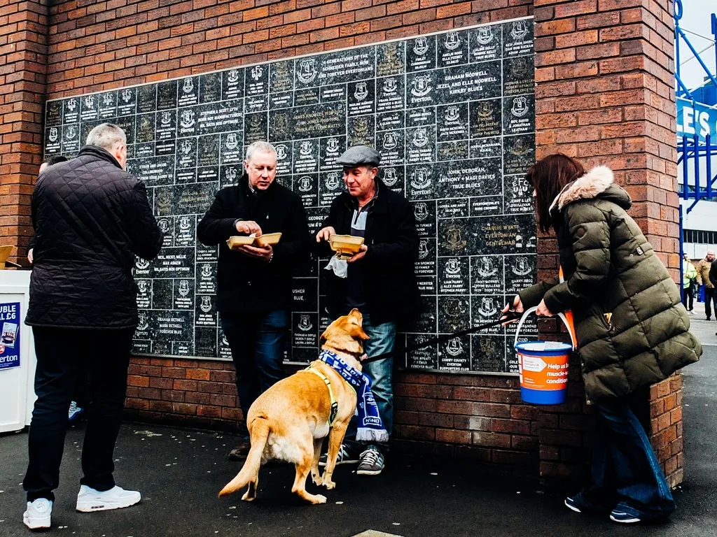 A group of people standing next to a brick wall